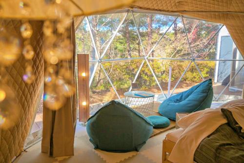 Shimojo mura的住宿－glampark Gekkabijin Nagano，客房配有蓝色枕头和窗户。