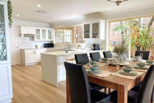 a kitchen and dining room with a wooden table and chairs at Aria waterview in Point Clare