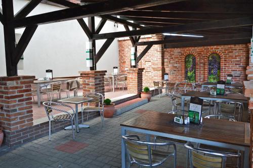 un patio con mesas y sillas en un edificio de ladrillo en Andante Pension & Restaurant, en Szentgotthárd