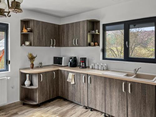 a kitchen with wooden cabinets and a sink and a window at Casa Șimon in Leordina