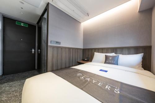 a bedroom with a large bed and a black door at Layers Hotel Busan Hadan in Busan