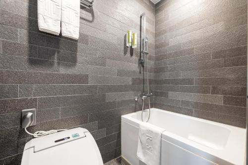 a bathroom with a toilet and a bath tub at Layers Hotel Busan Hadan in Busan