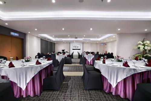 a banquet hall with tables and chairs with white and purple table settings at Neo+ Penang in George Town