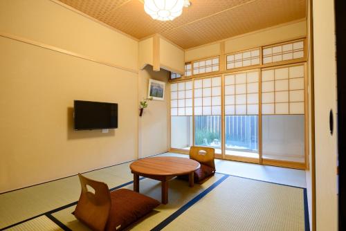 Zimmer mit einem Tisch, einem Stuhl und einem Fenster in der Unterkunft Luck You Kyoto in Kyoto