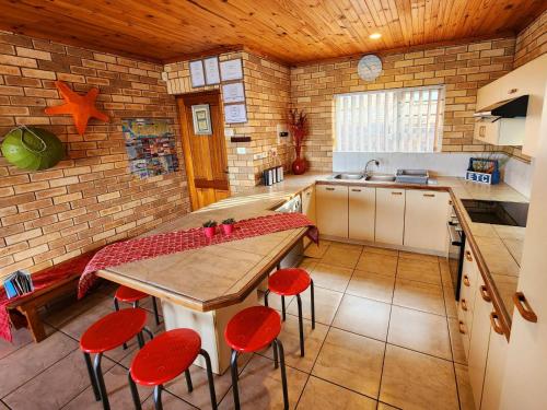 cocina con mesa de madera y sillas rojas en Surfpoint 9, en Jeffreys Bay