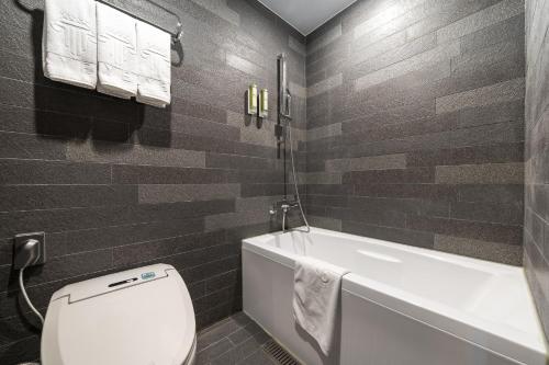 a bathroom with a white toilet and a bath tub at Layers Hotel Busan Hadan in Busan