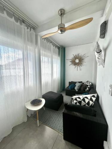 a living room with a couch and a ceiling fan at Lelaleu in Saint-Leu
