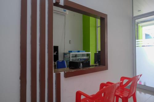 um espelho numa parede com duas cadeiras vermelhas em RedDoorz near Pakuwon Mall Solo Baru em Sukoharjo