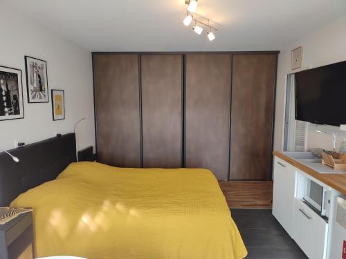 - une chambre avec un lit jaune et une télévision à écran plat dans l'établissement Les Gîtes De La Caneda, à Sarlat-la-Canéda