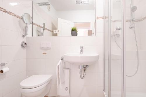 La salle de bains blanche est pourvue de toilettes et d'un lavabo. dans l'établissement Goldene Ruh Wohnung 203, à Grömitz