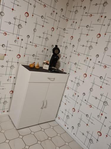 a white cabinet in a room with a patterned wall at Schönes Doppelzimmer mit Küche und Badezimmer in Elgersburg