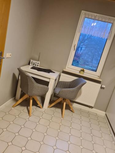 a desk and two chairs in a room with a window at Schönes Doppelzimmer mit Küche und Badezimmer in Elgersburg