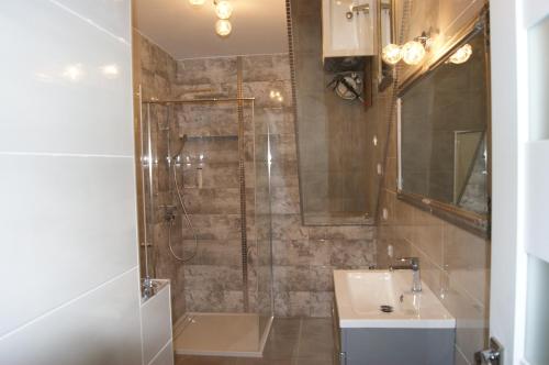 ein Bad mit einer Dusche und einem Waschbecken in der Unterkunft Kama Apartament Kamień Pomorski in Cammin in Pommern