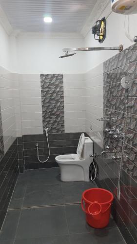 uma casa de banho com um WC e um chuveiro com baldes em SANS TEA VILLA em Jalpāiguri