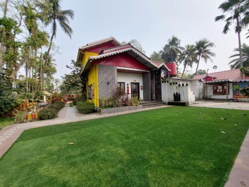 una casa con un césped verde delante de ella en SANS TEA VILLA, en Jalpāiguri