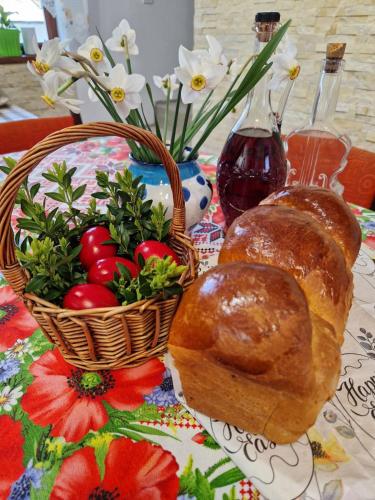 a table with two loaves of bread and a basket of vegetables at Casa Hera in Călimăneşti