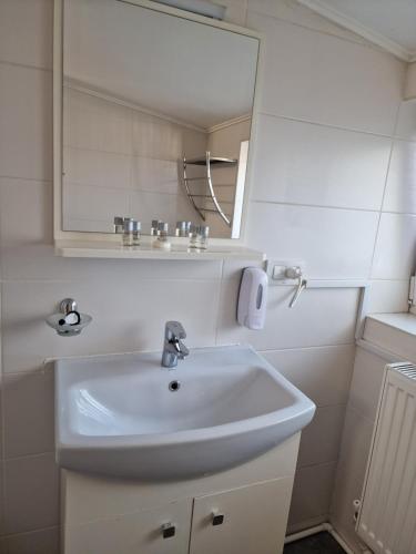 La salle de bains est pourvue d'un lavabo blanc et d'un miroir. dans l'établissement Stay Inn Rediu, à Iaşi