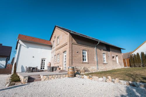 an old brick building on a gravel driveway at Magtár Villa in Bóly