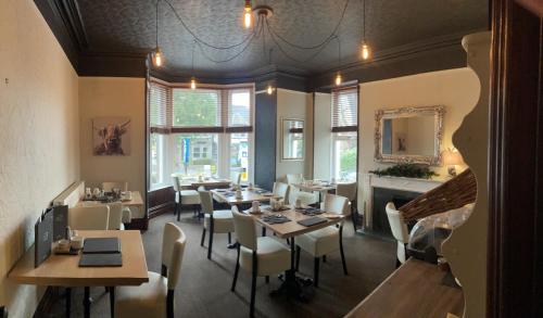 a restaurant with tables and chairs and a fireplace at Glenville House - Adults Only - Incl FREE off-site health club with swimming pool, hot tub, sauna & steam room in Windermere