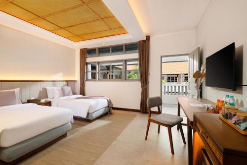 a hotel room with two beds and a desk at The Mahata in Legian