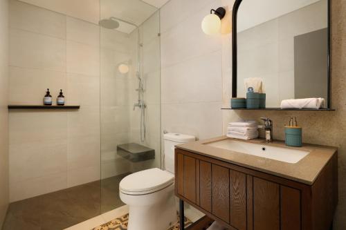 a bathroom with a toilet and a sink and a shower at The Mahata in Legian