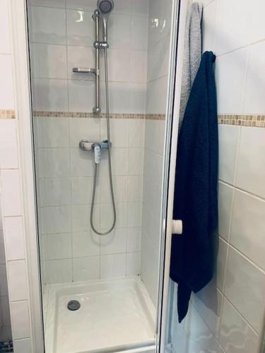 La salle de bains est pourvue d'une douche et d'une serviette bleue. dans l'établissement Tiny81 cozy city break appartment, à Clichy