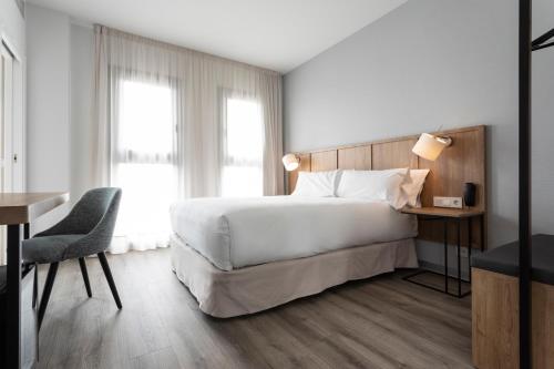 um quarto de hotel com uma cama grande, uma secretária e uma cadeira em Petit Palace Vargas em Sevilha