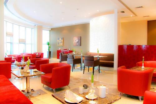 a restaurant with red furniture and tables and chairs at Icon Delux Hotel Apartments Al Barsha - Formerly Abidos in Dubai