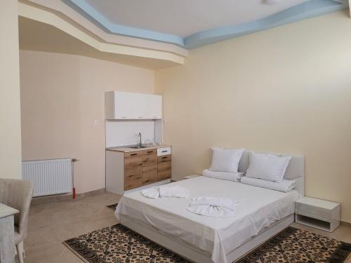 a white bedroom with a bed and a sink at Китанови- стаи за гости in Sliven