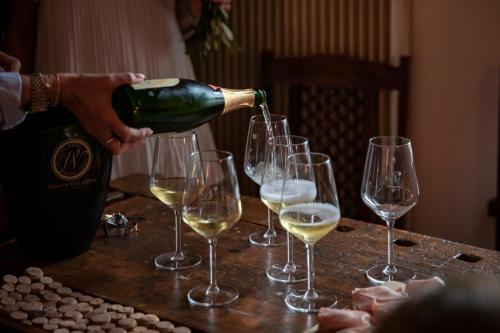 a person pouring wine into wine glasses on a table at Rooms Relais Art Borgocastello3 in Gorizia