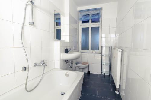 萊比錫的住宿－Balkon, Waschmaschine, TV, Einzelbetten, nahe Völkerschlachtsdenkmal，白色的浴室设有浴缸和水槽。