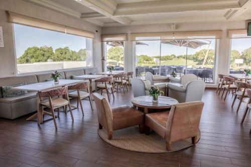 restauracja ze stołami, krzesłami i oknami w obiekcie Fairplay Golf & Spa Resort w mieście Benalup Casas Viejas