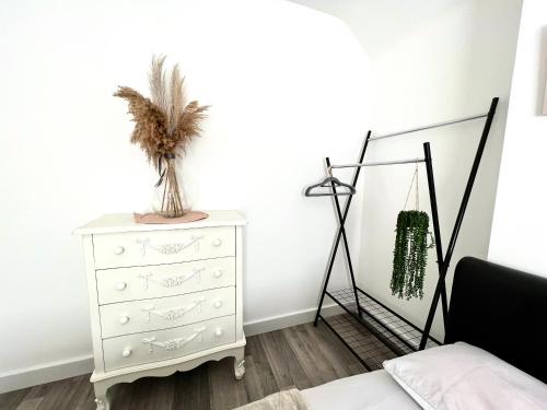 a bedroom with a white dresser with a plant on it at Beautiful Double Room for One Person in Hither Green