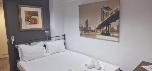 ein Schlafzimmer mit einem weißen Bett mit einem Bild an der Wand in der Unterkunft Cosy studio in Pilea Thessaloniki in Thessaloniki