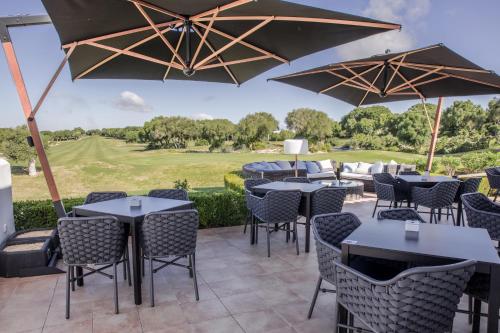 a patio at a hotel with tables and chairs and umbrellas at Fairplay Golf & Spa Resort in Benalup Casas Viejas