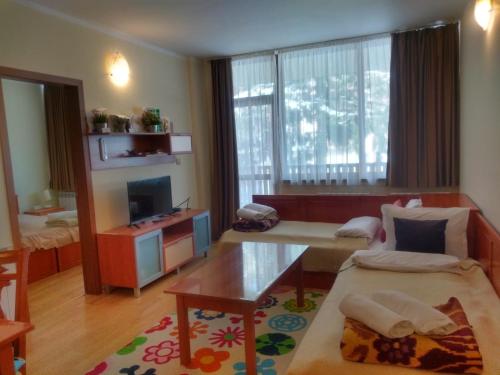 a living room with a couch and a tv at Kolimechkov Apartments Borovets in Borovets
