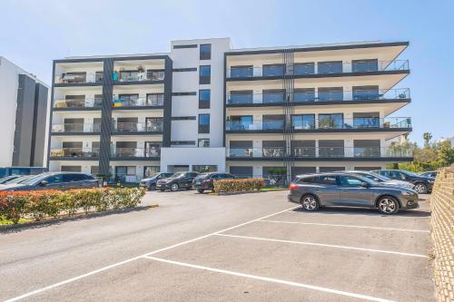 a parking lot with cars parked in front of a building at Monte Residence Beach e Pool in Portimão