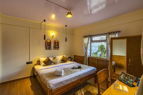 a bedroom with a bed and a table and a window at Zostel Homes Pedong, Kalimpong in Kalimpong