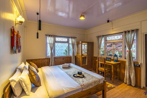 a bedroom with a bed and a desk and windows at Zostel Homes Pedong, Kalimpong in Kalimpong