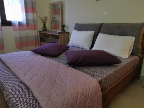 Una cama con almohadas moradas y blancas. en Fiore di Rodi - Private Pool, Jacuzzi and Barbecue, en Ialisos