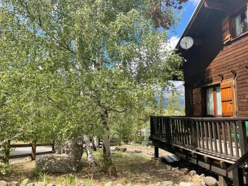 ein Baum neben einem Haus mit einer Veranda in der Unterkunft Sirolane, chalet au bord des pistes au Sauze in Enchastrayes