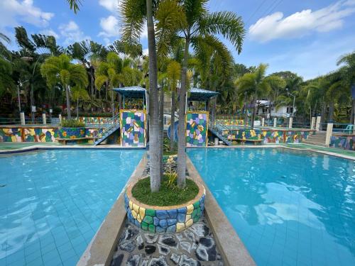 a swimming pool with a palm tree in the middle at Poracay Resort powered by Cocotel in Porac