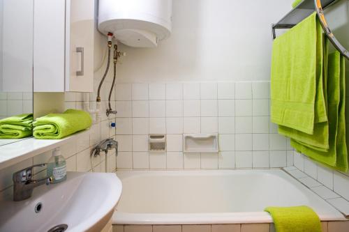 a bathroom with a tub and a sink and green towels at Süllő utcai apartman Fonyód VÍZPARTI és PANORÁMÁS! ON THE WATERFRONT and with Balaton panorama! in Fonyód