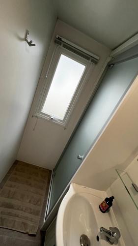 une salle de bain avec un lavabo et une fenêtre dans l'établissement Mobil homme proche de la mer, au Grau-du-Roi