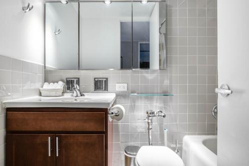 a bathroom with a sink and a toilet and a mirror at Gold Coast 2BR w Gym Roof nr Water Tower CHI-389 in Chicago