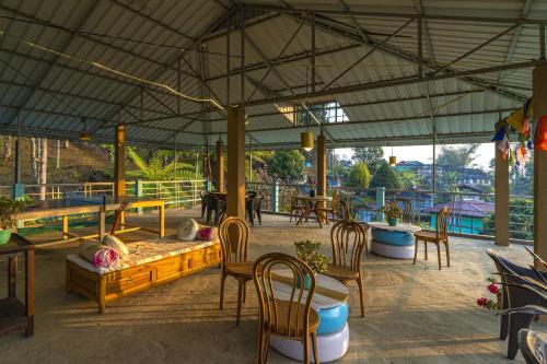 een patio met tafels en stoelen en een grote tent bij Zostel Homes Pedong, Kalimpong in Kalimpong