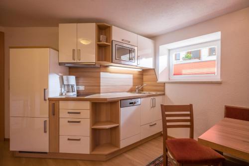 a kitchen with white cabinets and a table and a window at Mountainpeak in Mayrhofen