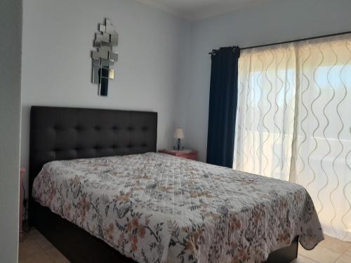 a bedroom with a bed with a comforter and a window at Residence 1000 Roses in Moncarapacho