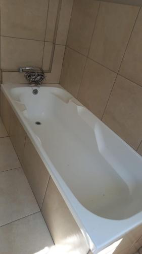 a white bath tub in a bathroom with tiles at Lavender Lane in Ladysmith