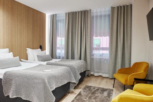 a hotel room with two beds and a chair at Hotel Verso in Jyväskylä